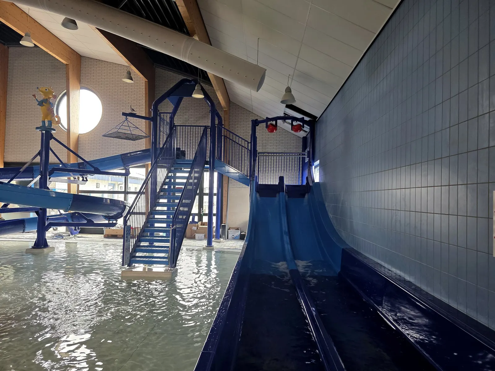 Brede blauwe dubbele glijbaan met trap in de waterspeeltuin van Paardekreek