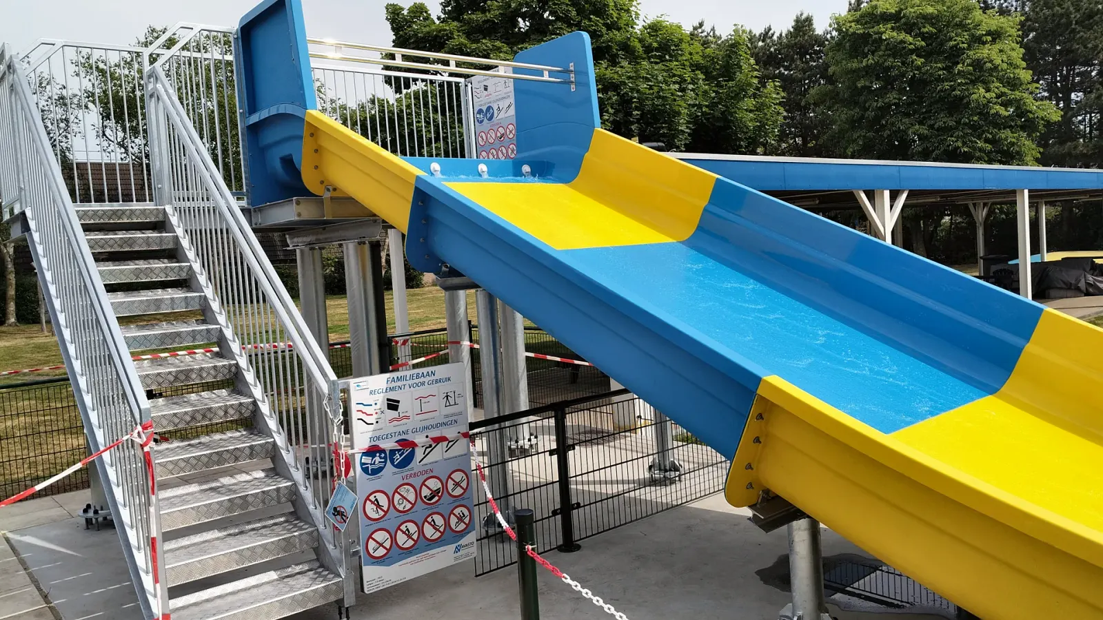 Glijbaan met stalen trap en veiligheidsbord bij zwembad 't Kuipke