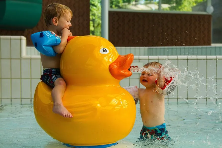 Kinderen spelen op een badeend-dierfiguur in het peuterbad van Camping de Paal