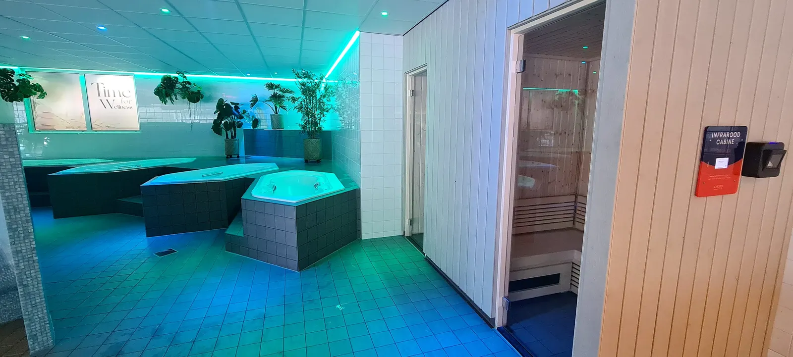 Wellnessruimte met whirlpools, sfeerverlichting en een infraroodcabine met betaalpaneel in De Waterwyck in Steenwijk
